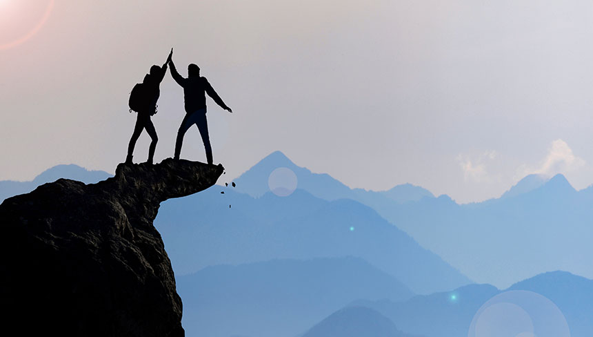 Zwei Personen erreichen den Gipfel eines Berges